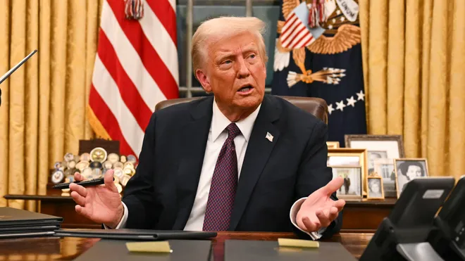 trump at desk with hands out
